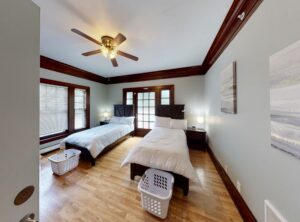 Clean, airy room with twin detox beds in Kirkland Washington. Room with grey walls, cherry wood molding, hardwood floors, white bedding, and bright lighting
